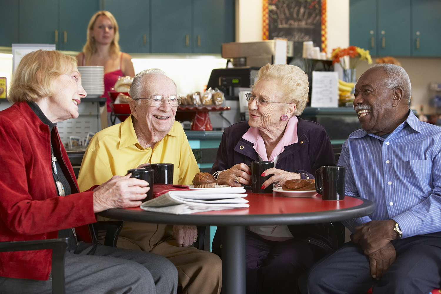 four people sitting at a table in a coffee shop