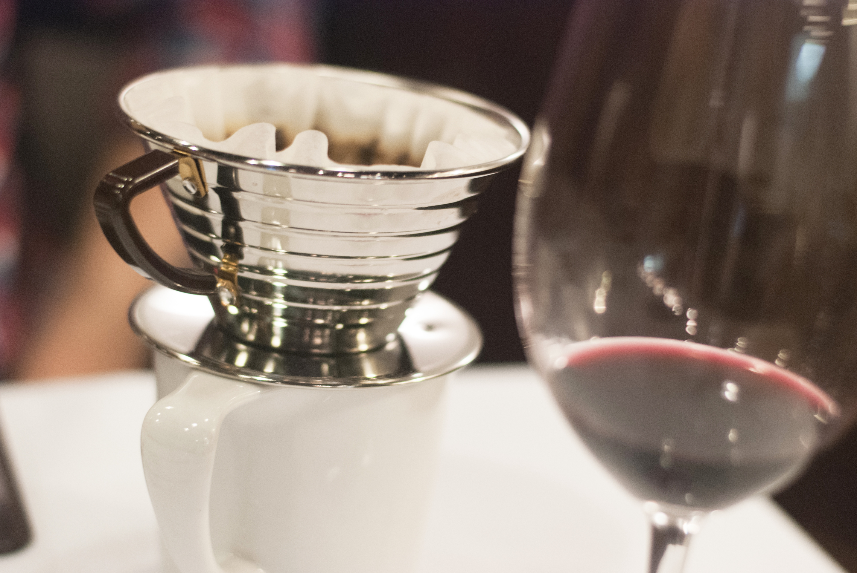 Close up shot of Kalita brewer on mug next to out of focus wine glass